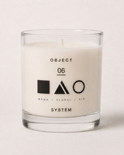 A white scented candle in a clear glass jar with minimalist black text and geometric logos, labeled 'OBJECT 06 SYSTEM'.