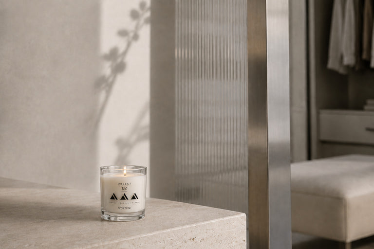 Composition 02 green floral candle burning on a stone surface in a softly lit bedroom.