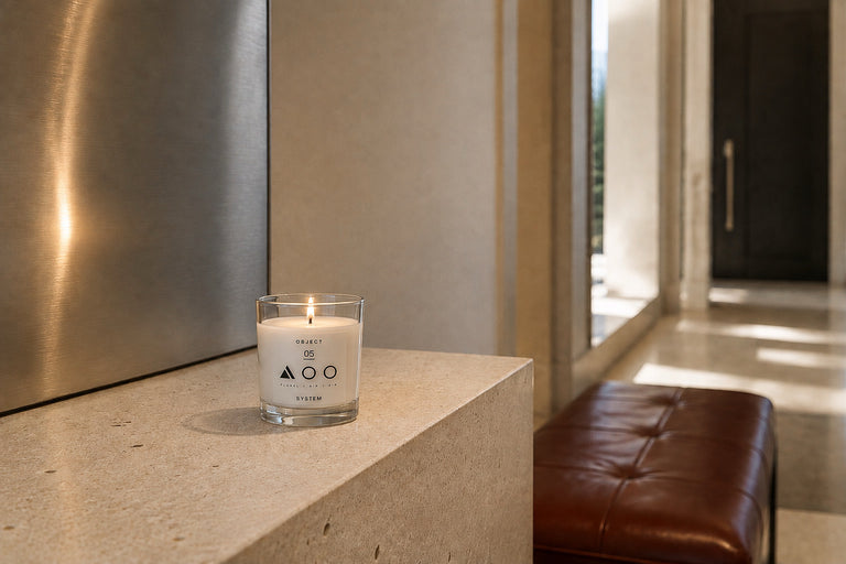 Composition 05 floral and air candle burning on a stone console in a warm modern interior.